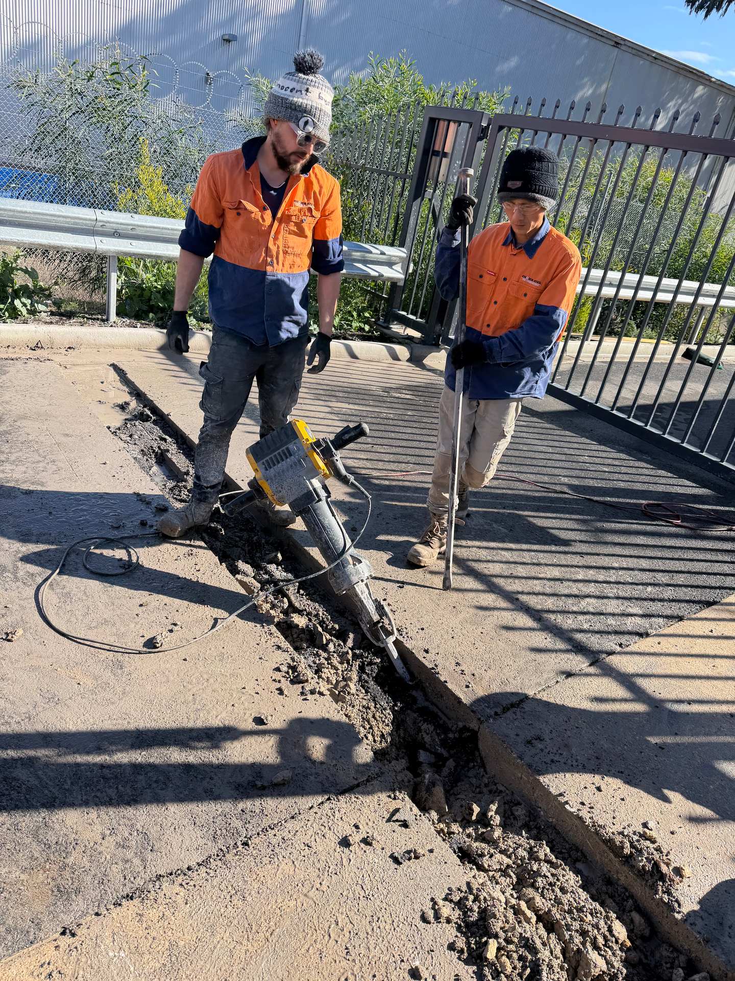Crew cutting and breaking concrete along a wall line