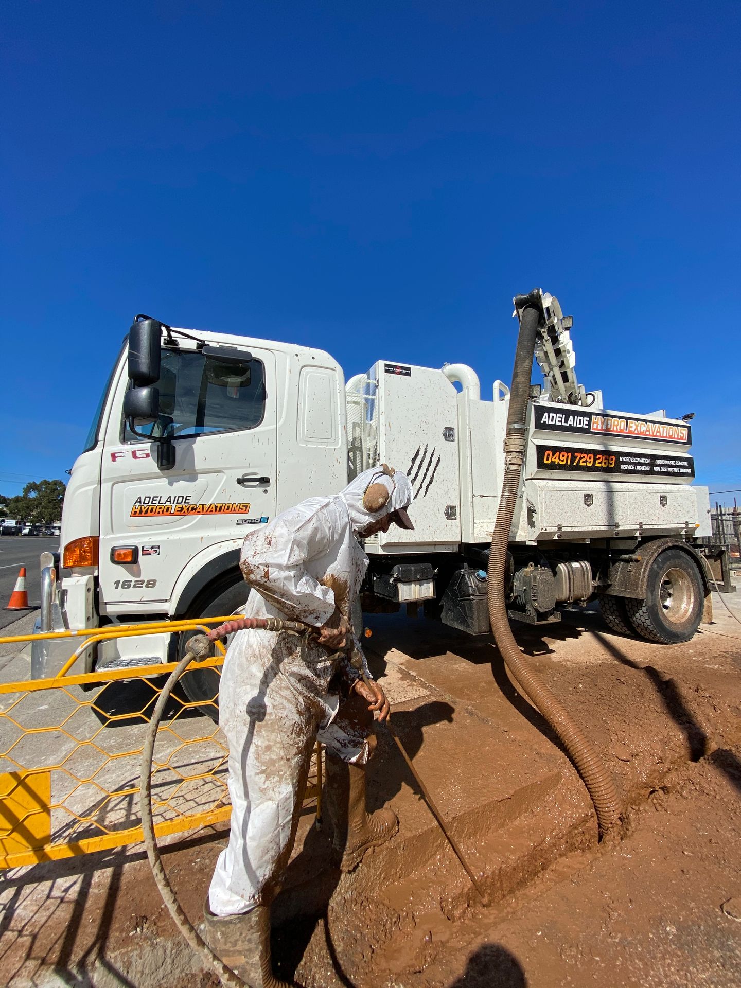Hydro excavation operator working the vacuum hose beside the truck